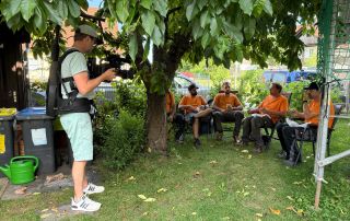 Hinter den Kulissen – Imagefilme Kameramann filmt eine Gruppe von Mitarbeitern welche gerade im Grünen eine Pause machen