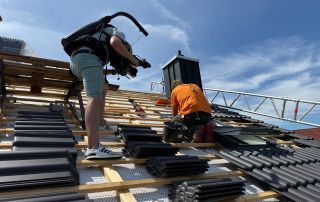 Hinter den Kulissen – Dachdeckerei Dachdecker werden bei ihrer Arbeit auf einem Dach gefilmt